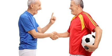 Two elderly soccer players shaking hands